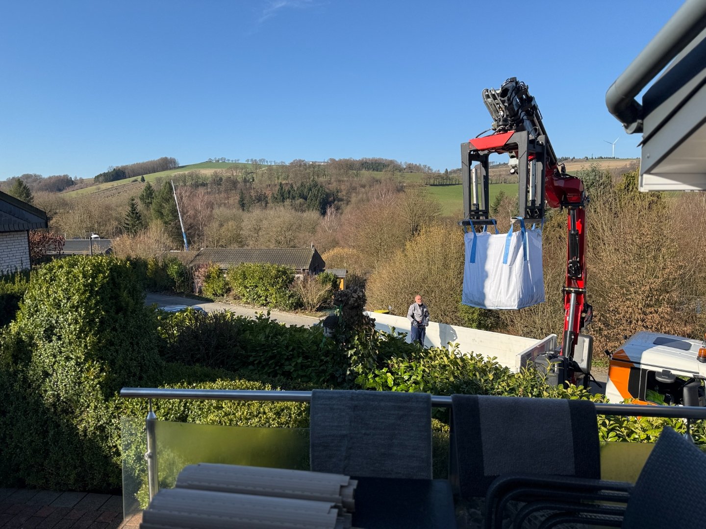 Kran hebt Big Bag mit Baumaterial über die Terrasse